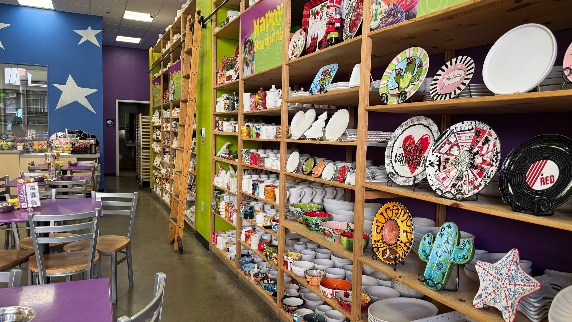 As You Wish Pottery studio shelves with painted and unpainted pottery pieces.