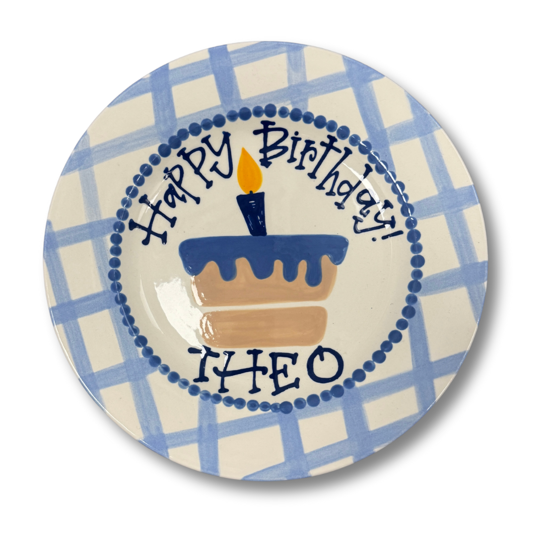 Decorative plate with 'Happy Birthday Theo' text and cake illustration on a blue and white checkered background.
