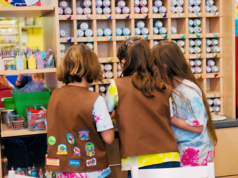 Children in Brownie uniforms standing in front of a cubby of paint bottles