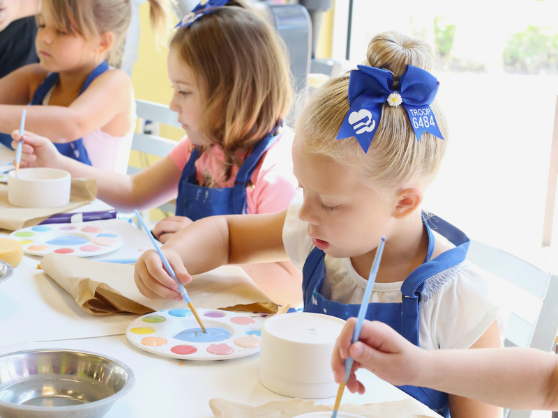 Daisy Girl Scouts painting pottery at a badge workshop