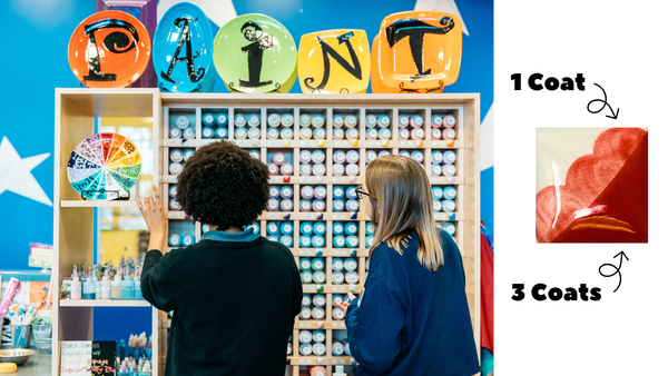 Two people looking at a display of paint bottles with color swatches above them.