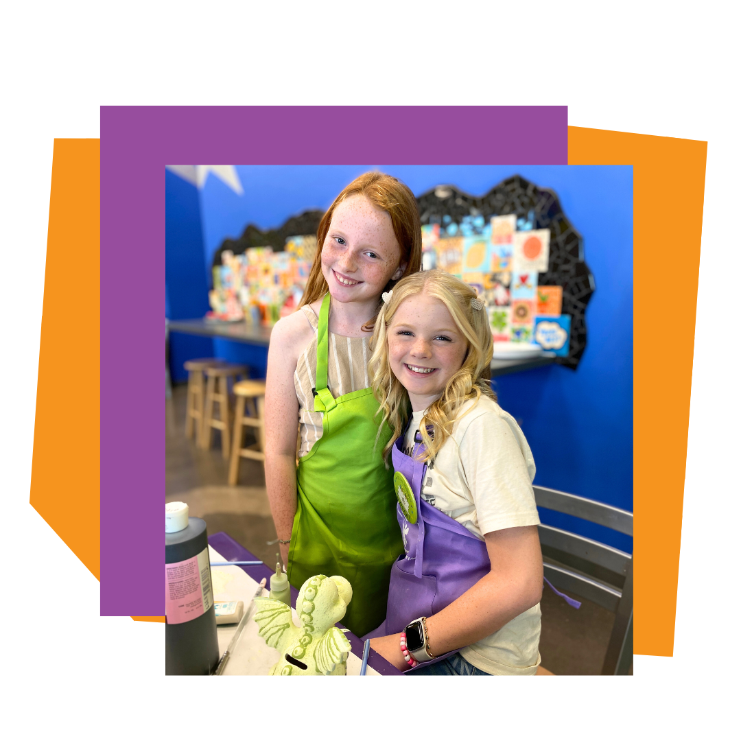 Two children in aprons standing in an As You Wish Pottery studio setting with colorful decorations at a birthday party